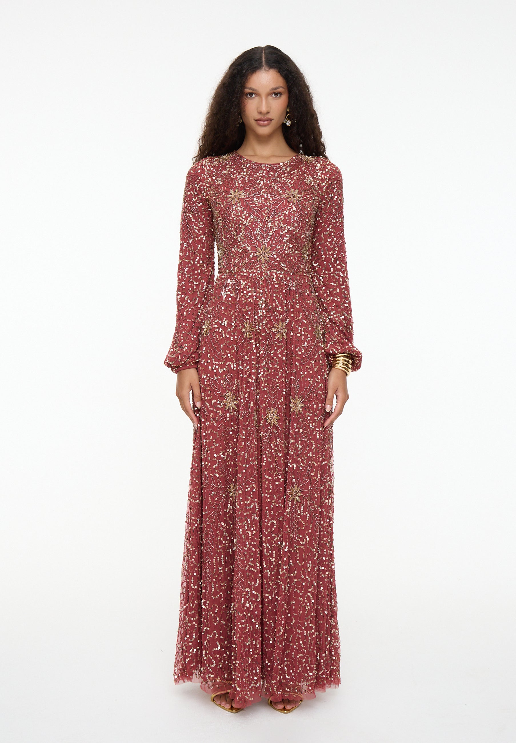 Woman wearing a long, patterned dress on a white background